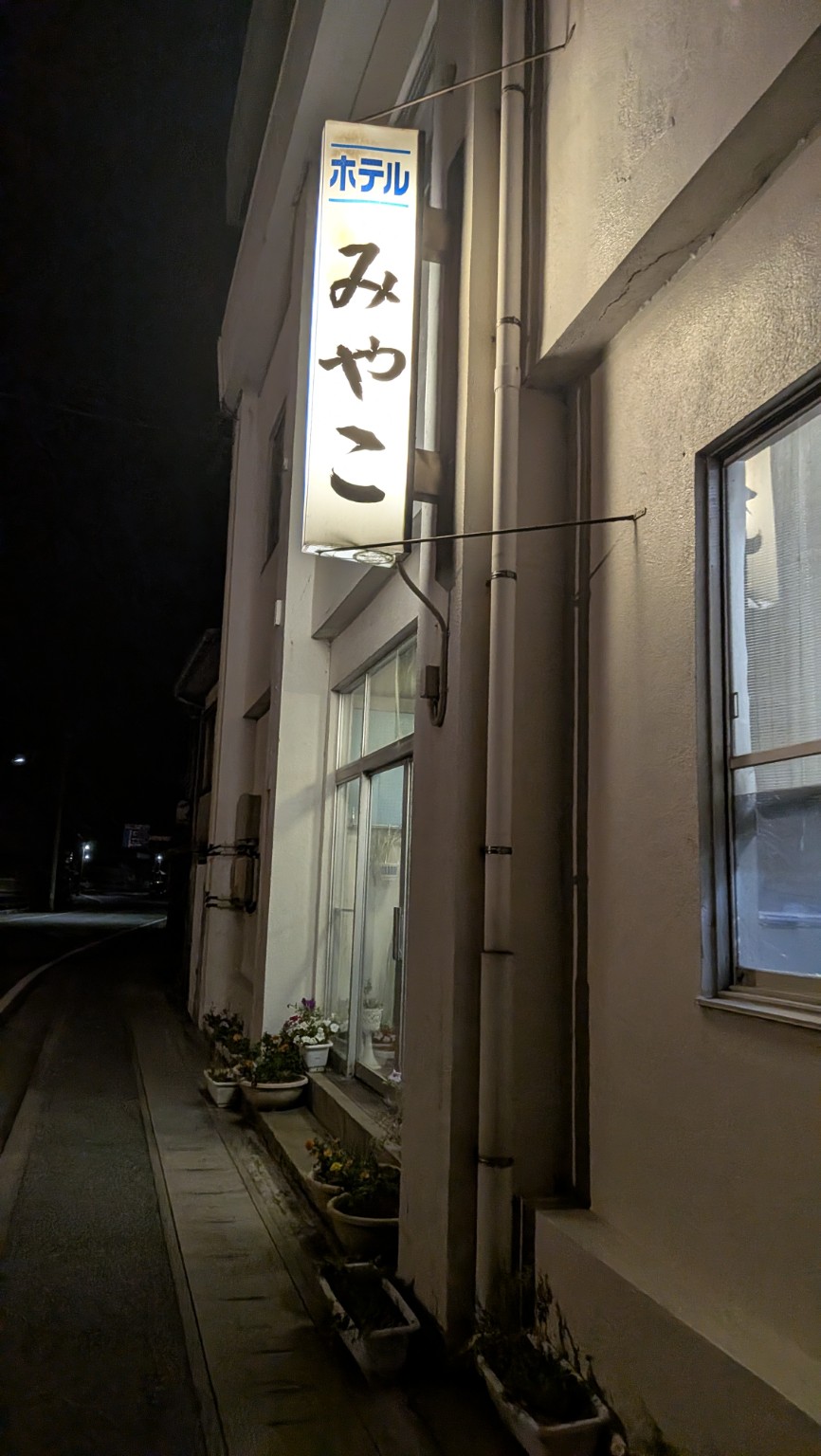 夜に撮影した佐渡ホテルみやこの看板と外観